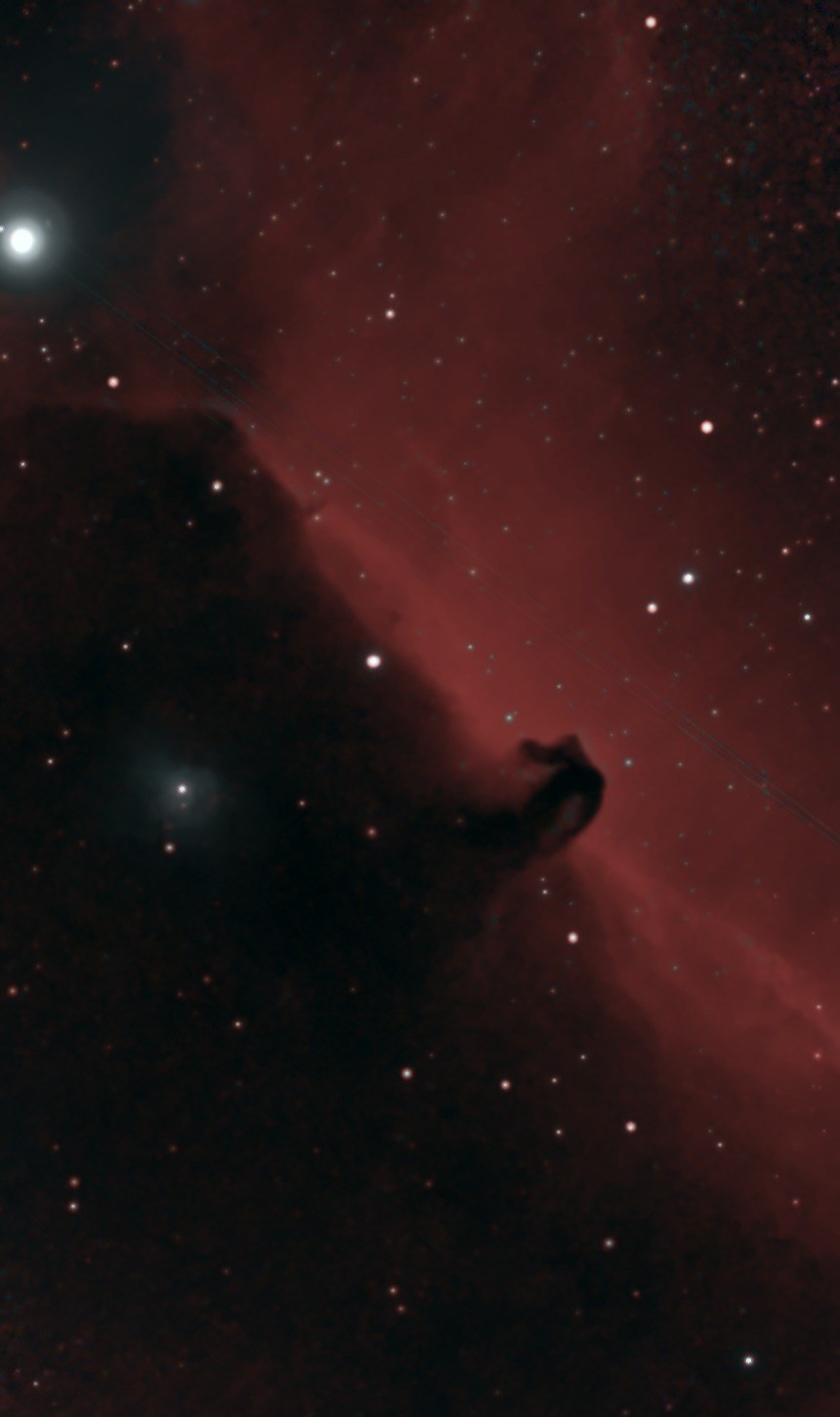 The Horsehead Nebula photographed from Lakeway, Texas with a ZWO Seestar S50: a dark horse-head silhouette of dust rising from a black cloud against a glowing red curtain of hydrogen, with the bright belt star Alnitak at upper left and the small glowing nebula NGC 2023 in the dark cloud below it.
