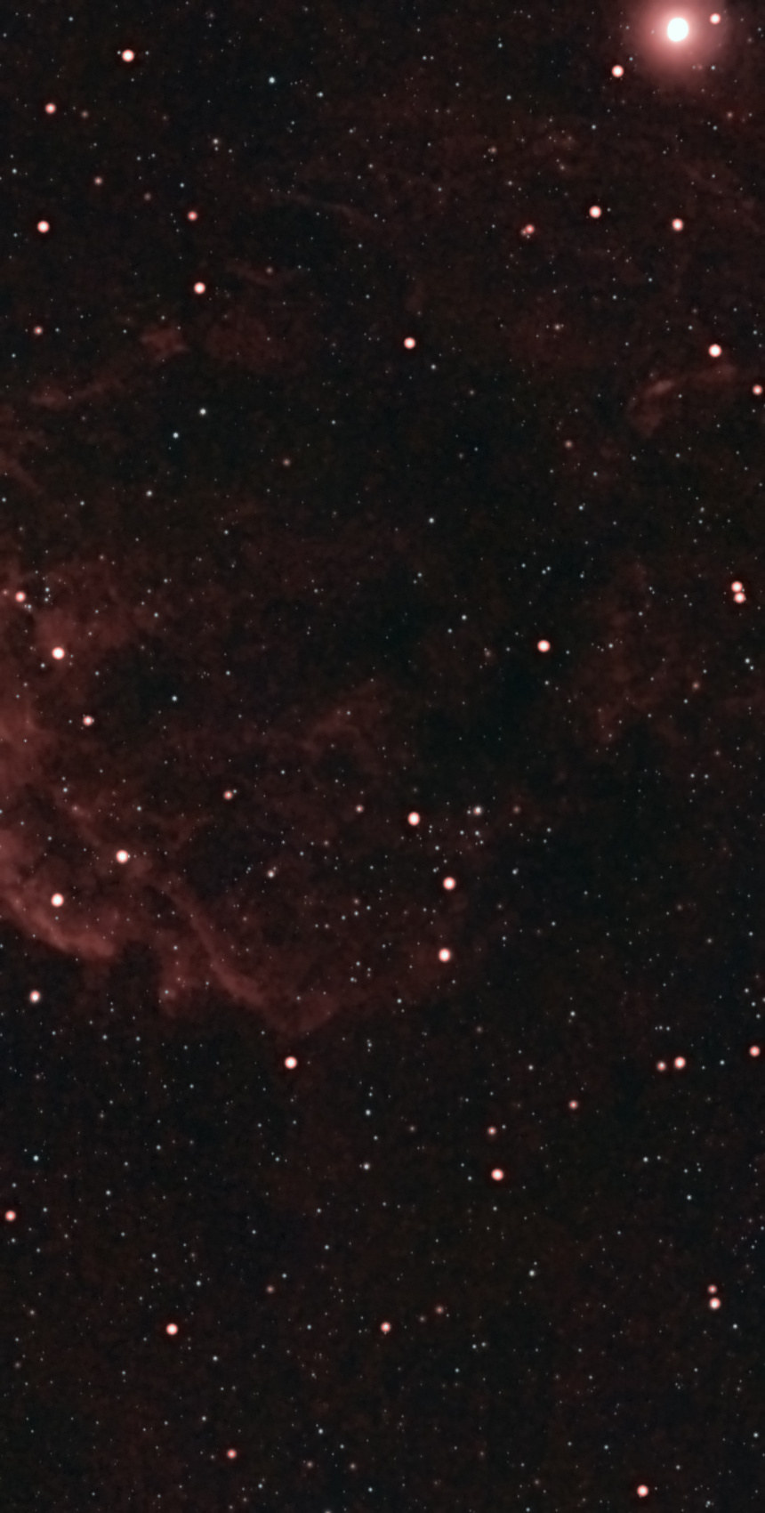 The Jellyfish Nebula (IC 443) from Lakeway, Texas with a ZWO Seestar S50 — the bright shock arc curving along the left side of the frame with braided red filaments, fainter wisps of the shell across the upper frame, and the bright star Eta Geminorum at the top right corner.