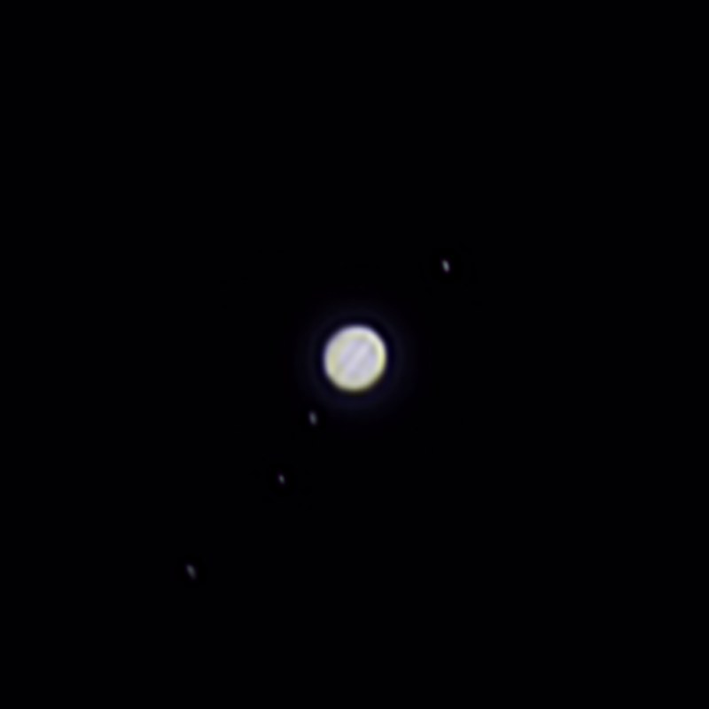Jupiter and its four largest moons photographed from Lakeway, Texas with a ZWO Seestar S50 — the planet's disk with visible cloud bands, and all four Galilean moons strung in a diagonal line around it.
