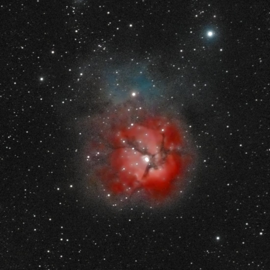 The Trifid Nebula (M20) photographed from Lakeway, Texas with a ZWO Seestar S50 — a small pink emission nebula divided into three lobes by dark dust lanes, with a bright young star at its center.