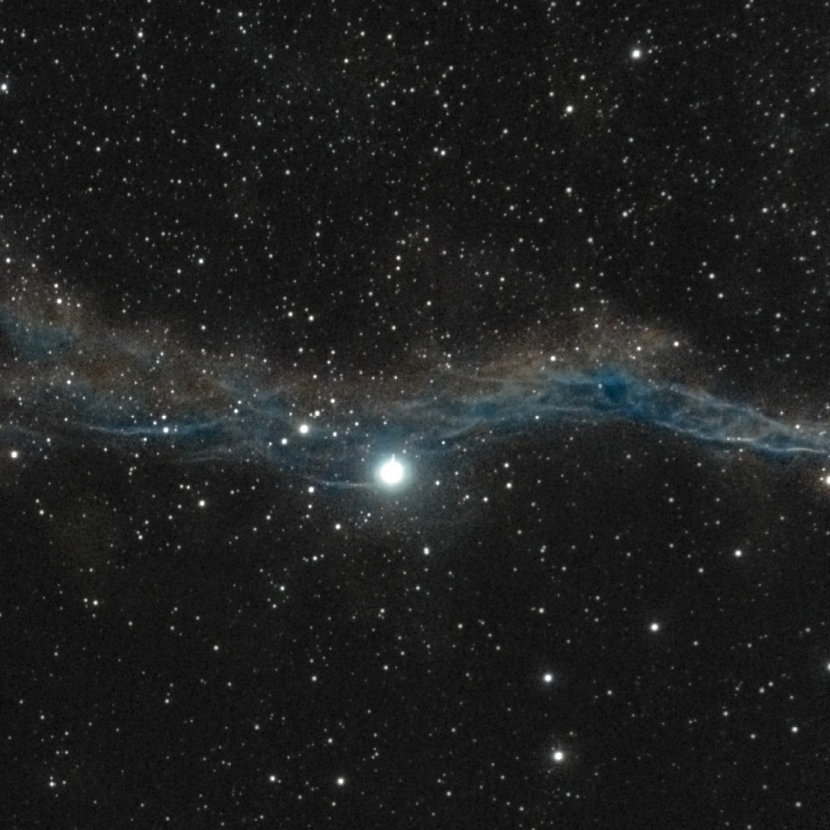 The Witch's Broom (NGC 6960, Western Veil) photographed from Lakeway, Texas with a ZWO Seestar S50 — a braided blue-white filament shaft running through the bright star 52 Cygni, with red nebulosity flanking it.