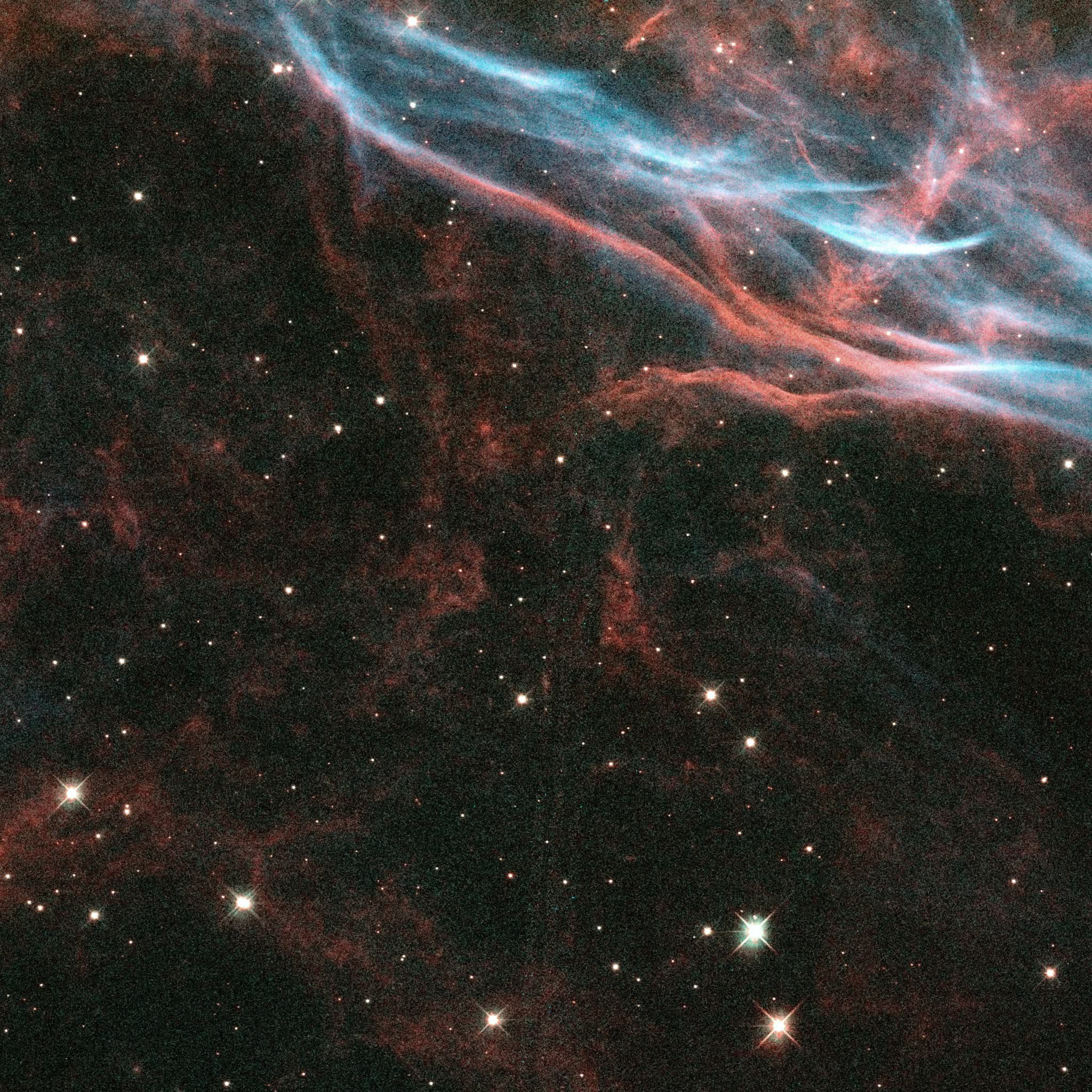 A section of the Veil Nebula from Hubble WFC3 data reprocessed by Kyle Eberly — braided teal oxygen ribbons and red hydrogen filaments sweeping diagonally across the upper frame, above a dark field laced with faint red gas.